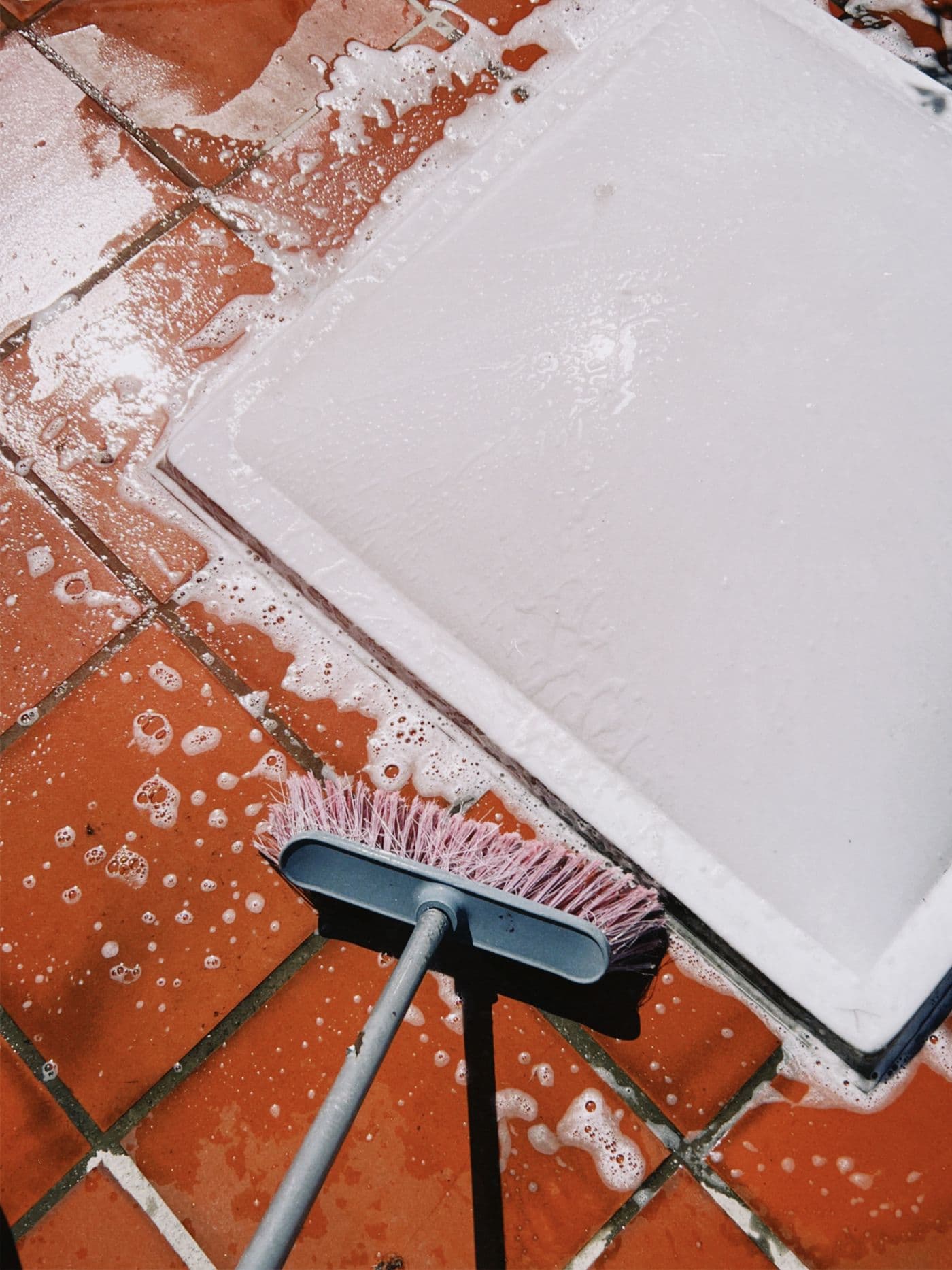 Soapy bathroom tile being scrubbed clean along the grout lines