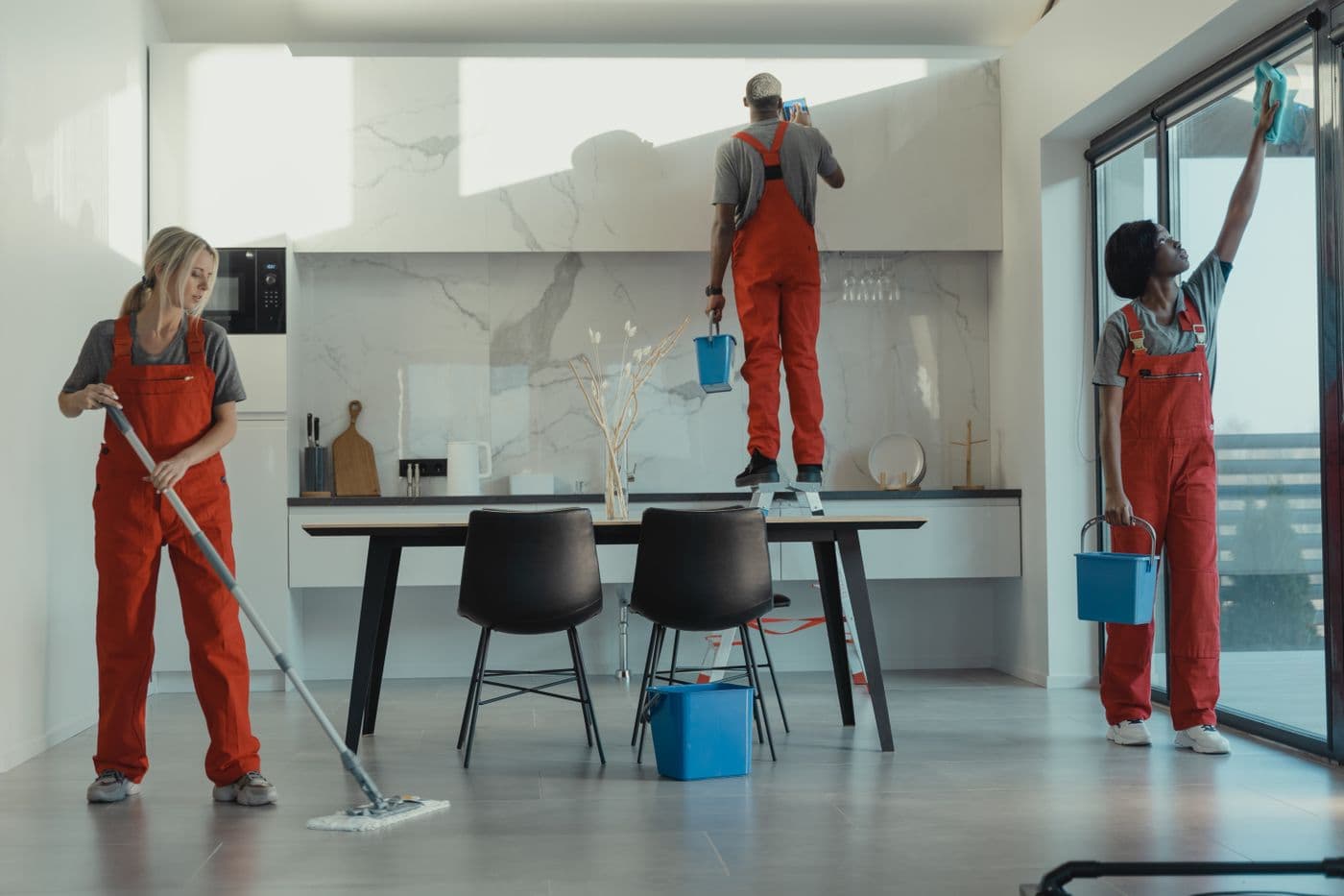 A cleaning crew in uniform working together through a dining room
