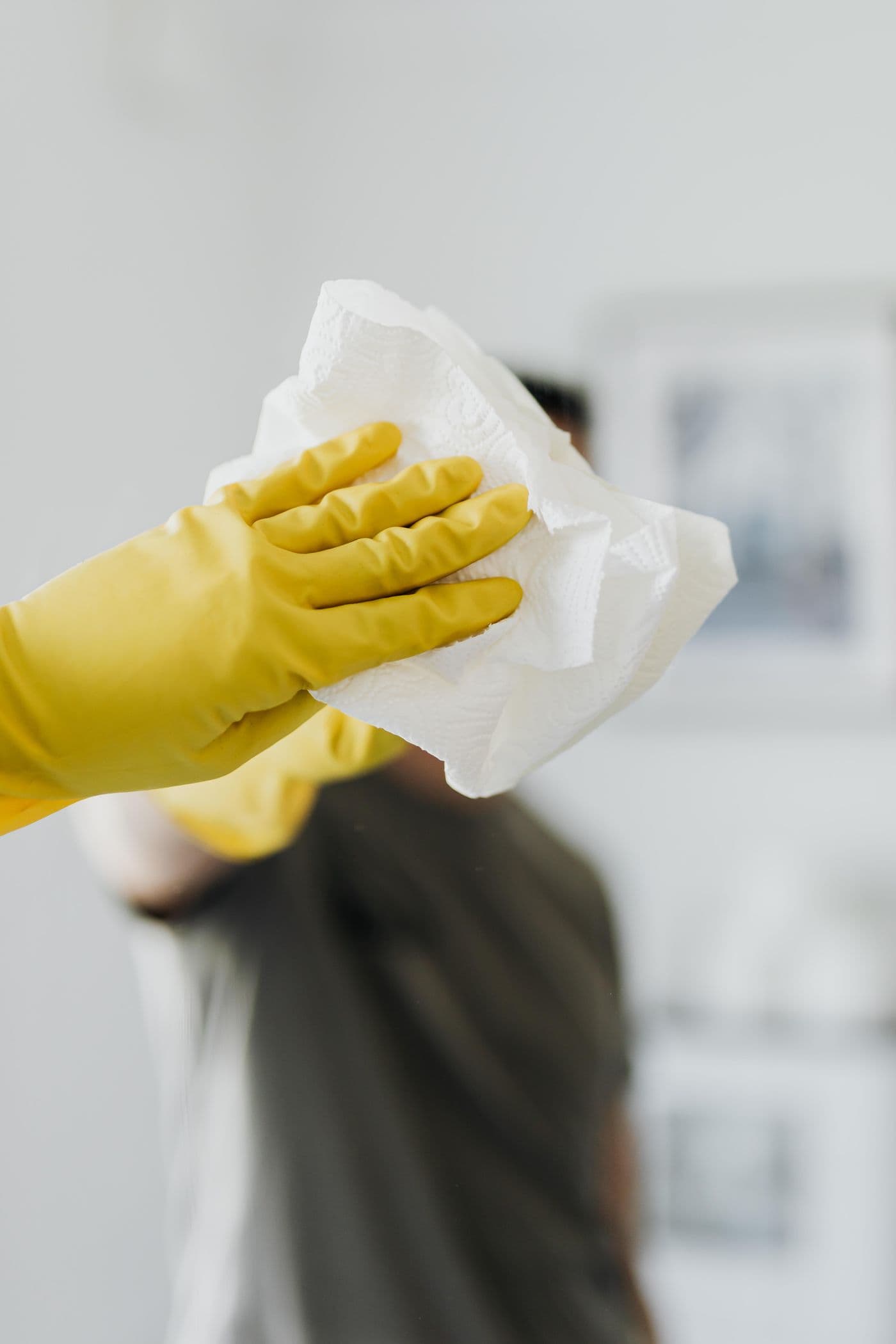 Gloved hand wiping a bathroom mirror until it is streak free